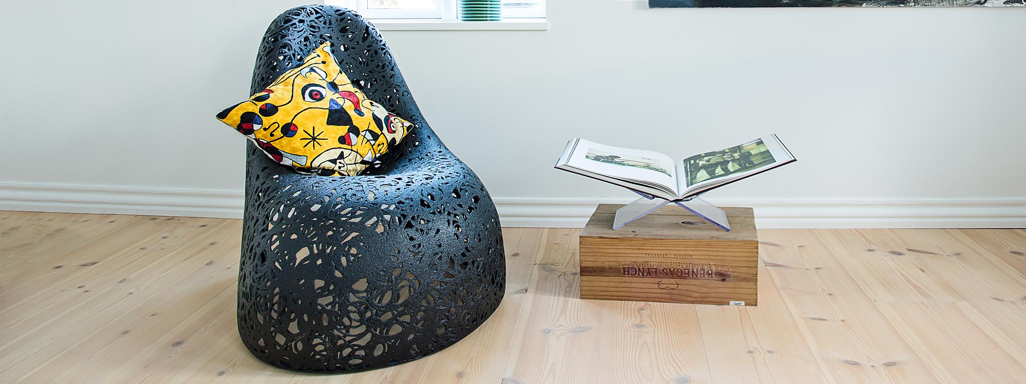 Image of black Self lounge chair by Unknown Nordic, shown inside a home next to magazine rack