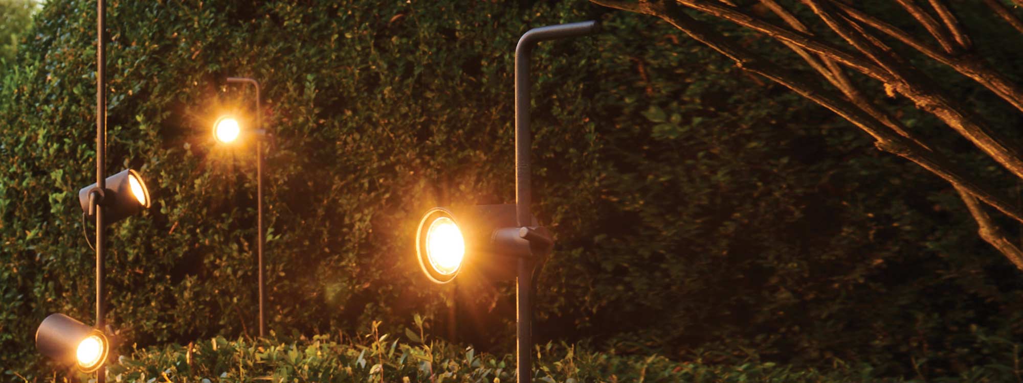 Image of 3 Royal Botania Spotty post outdoor spotlights orientated in different directions in a nighttime garden