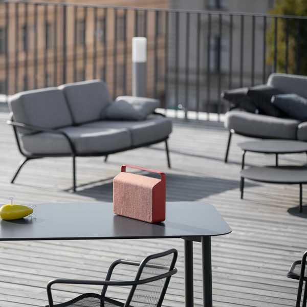 Image of Starling garden table and chair on rooftop terrace, with Starling modern outdoor sofas in the background