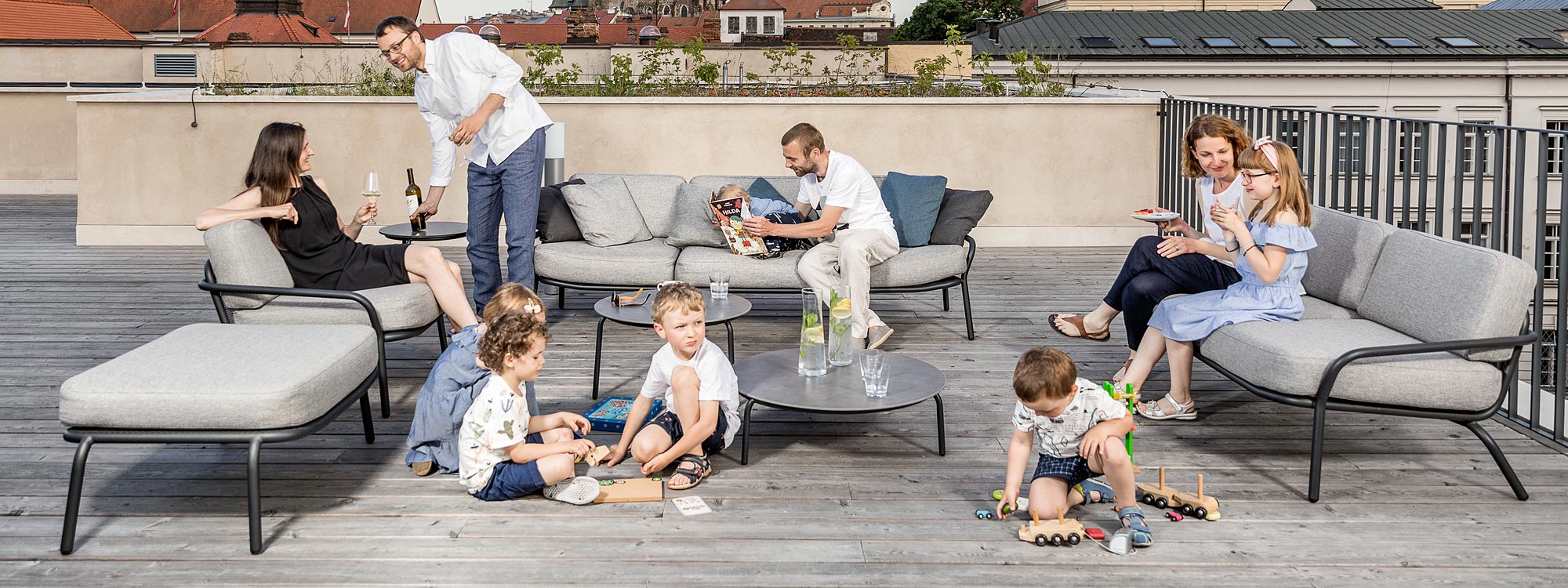 Image of adults and children partying on and around Todus Starling modern outdoor lounge furniture on wooden decked rooftop