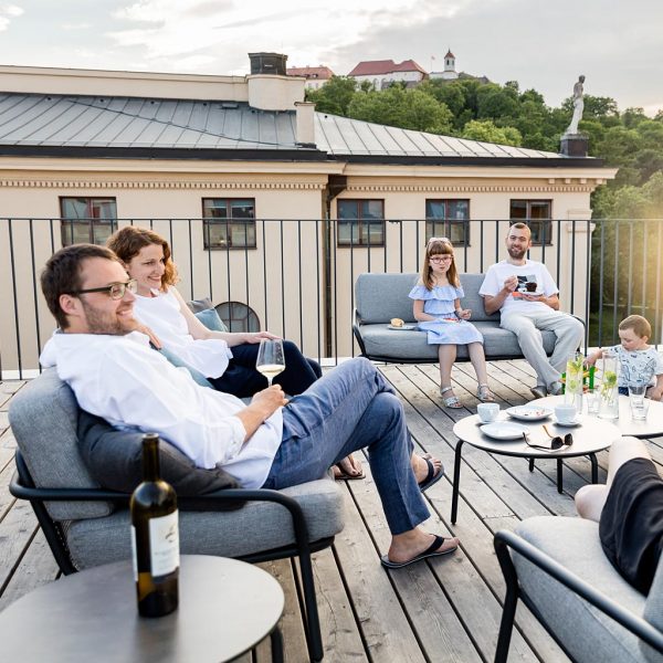 Image of adults and children relaxing together on Todus Starling modern outdoor sofas, shown on rooftop terrace