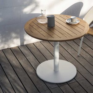 Image of RODA Stem circular bistro table with white base and planked teak table top, shown on wooden decked terrace