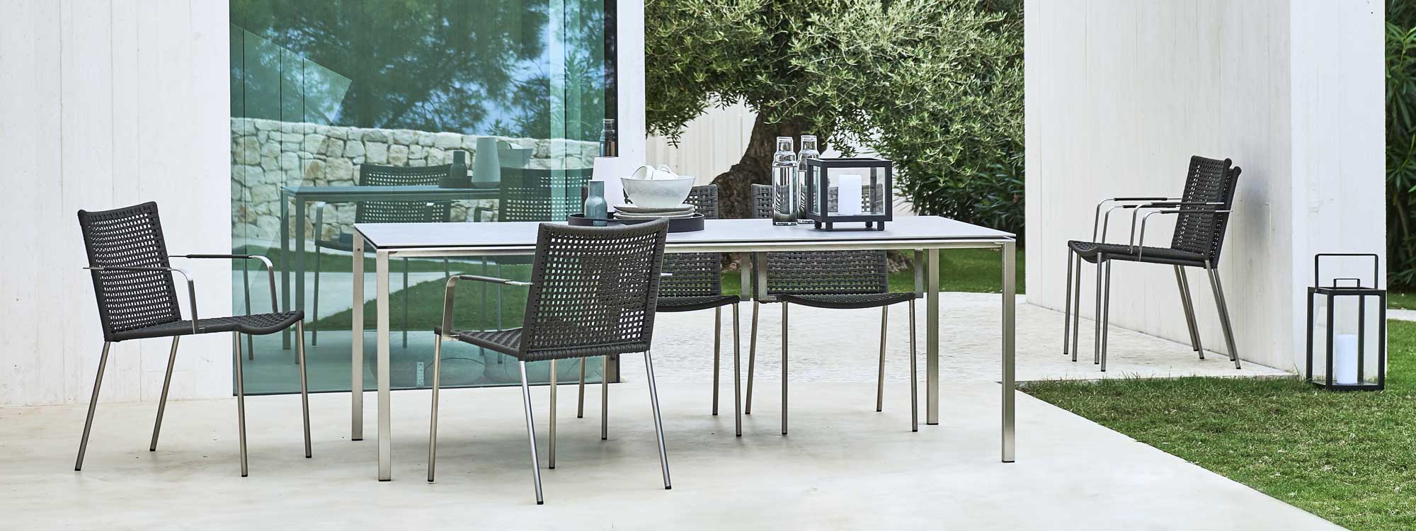 Image of Straw stainless steel chairs and Pure dining table by Caneline, shown on sleek modern terrace
