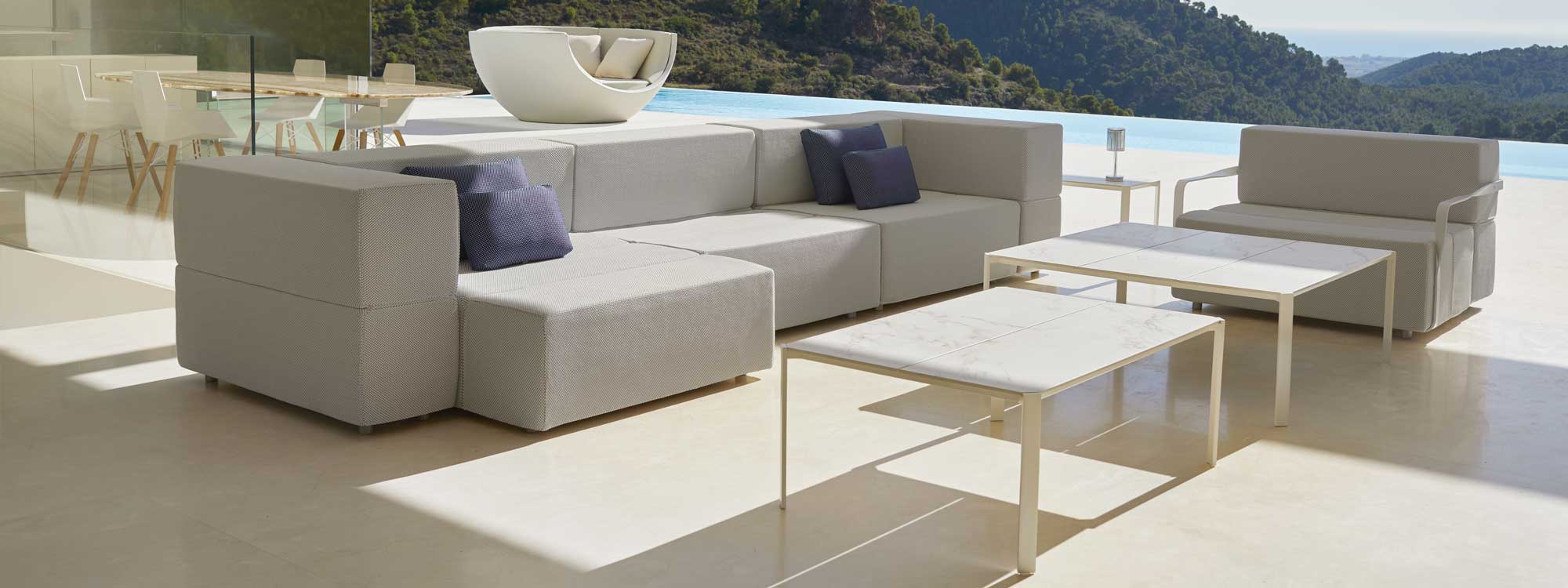 Image of Vondom Tablet modern garden sofa and lounge chair on terrace with horizon swimming pool and hills in the background