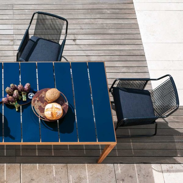 Image of aerial view of RODA Teka teak garden table with table top in slats of Sapphire glazed ceramic, together with Harp modern outdoor chairs
