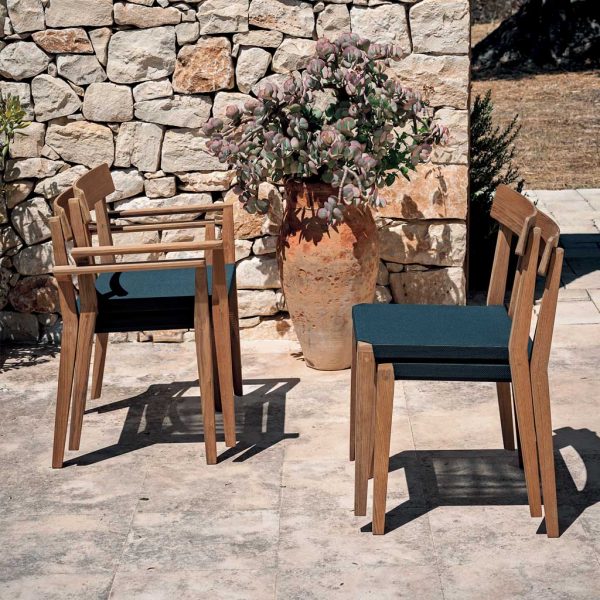 Stacking Teka teak garden chairs on sunny courtyard