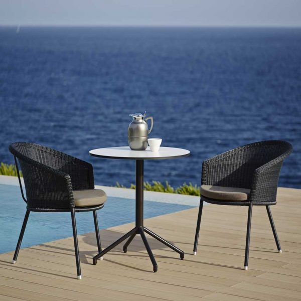 Image of Trinity black garden seats by Caneline, with sea in background.