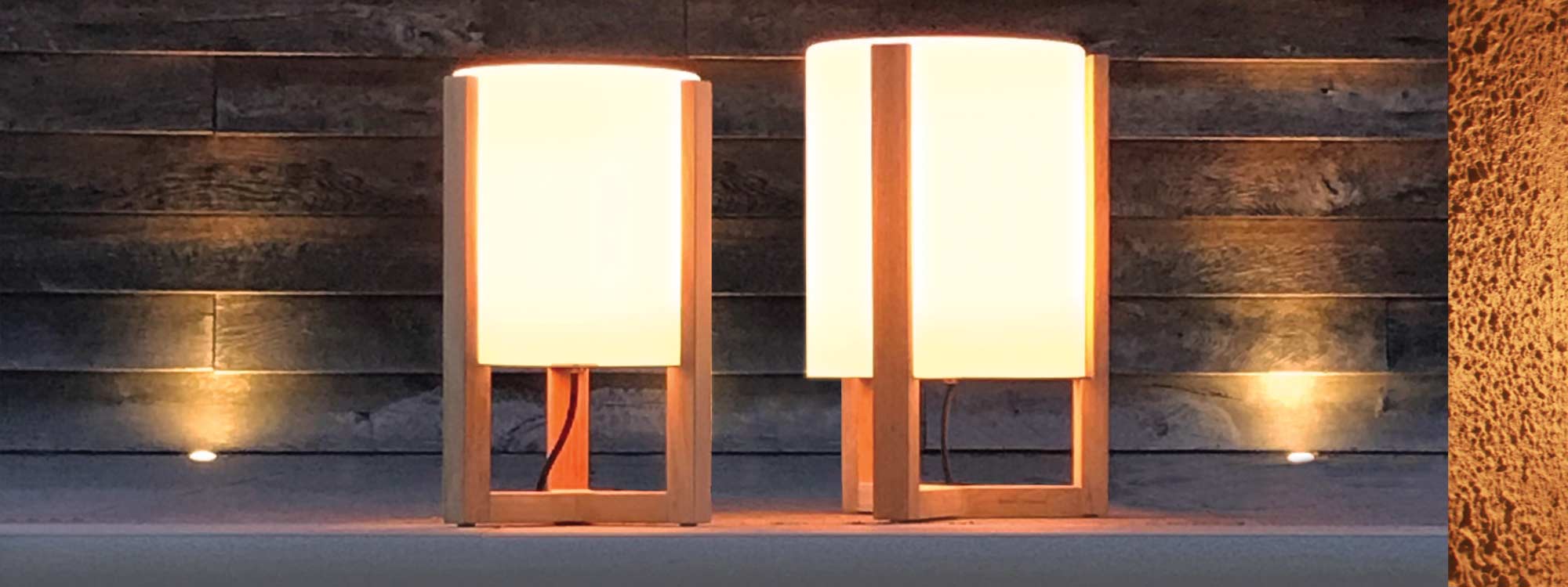 Image of pair of lit Royal Botania Tristar electric garden lanterns with teak frames and hand-blown opal glass lampshades