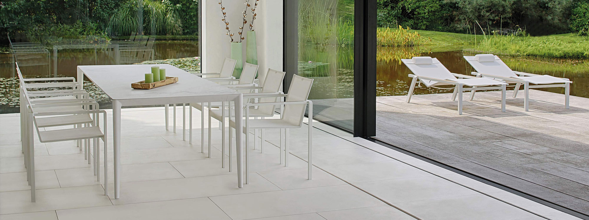 Bianco Statuario ceramic U-nite table & white Alura garden chairs in a garden room.