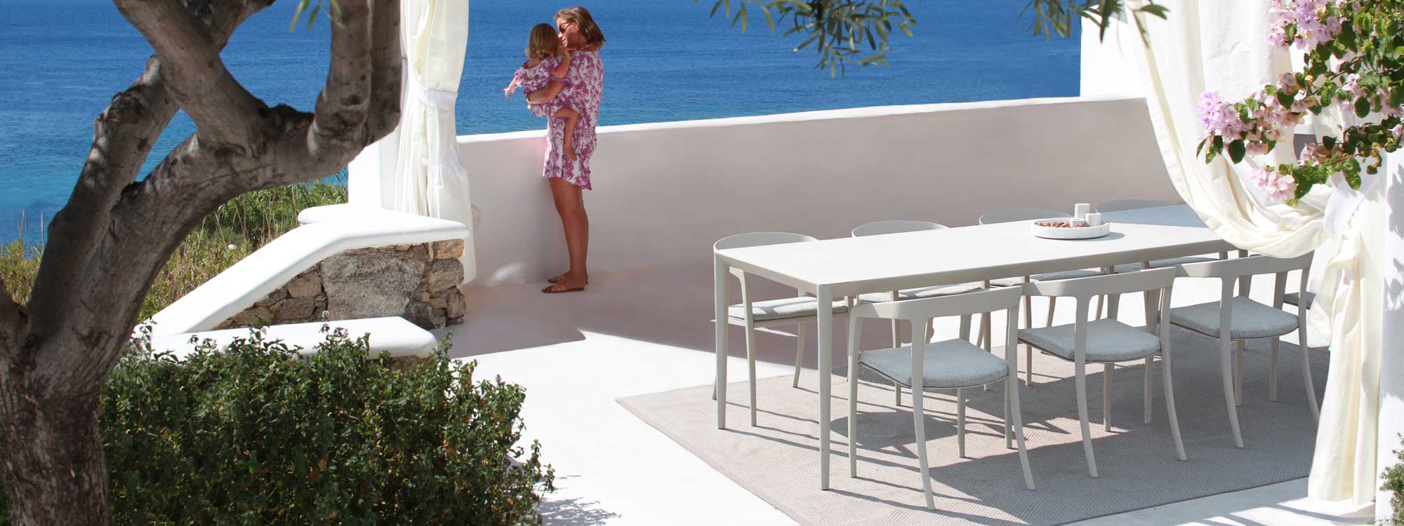 Image of Royal Botania Jive & U-NITE outdoor dining furniture in white with azure Ionian sea in background