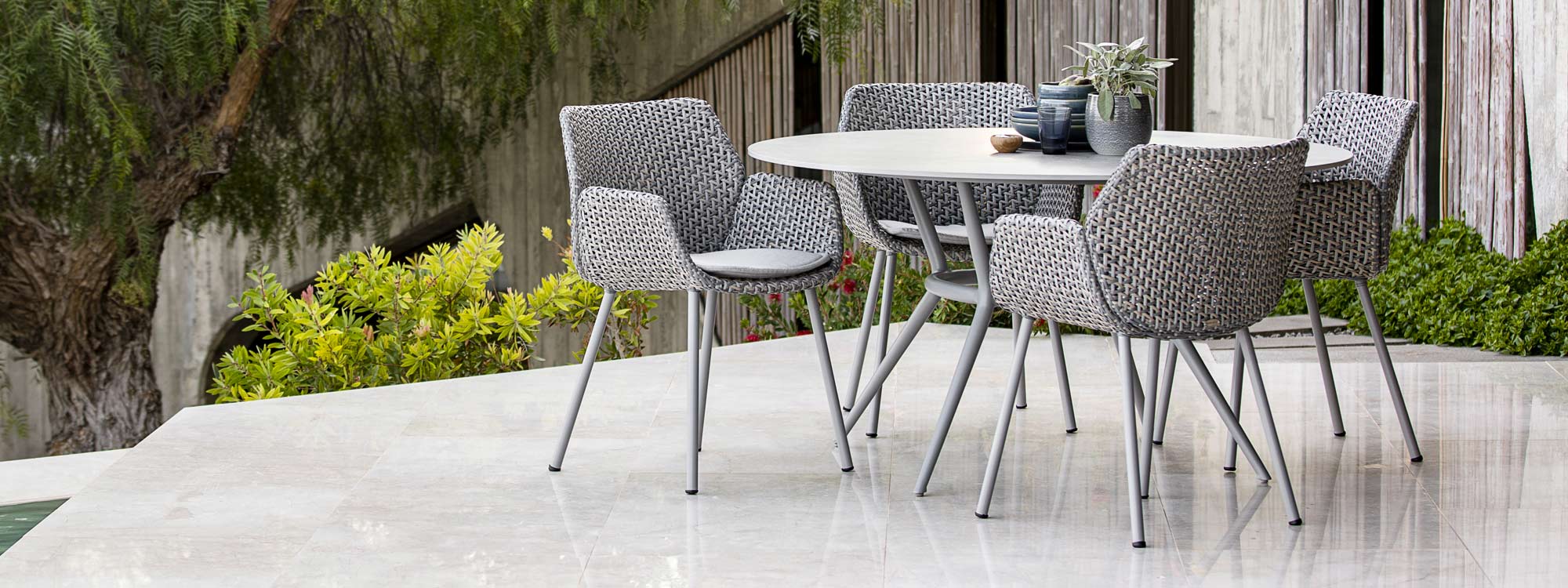 Image of Vibe split cane garden chairs around Joy round garden table by Cane-line