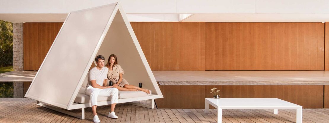Image of Vondom Vineyard white twin daybed with sulky young couple sat within, shown around courtyard poolside