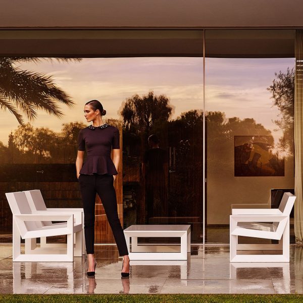 Image of woman stood next to Vondom Frame modern outdoor lounge furniture on terrace at dusk