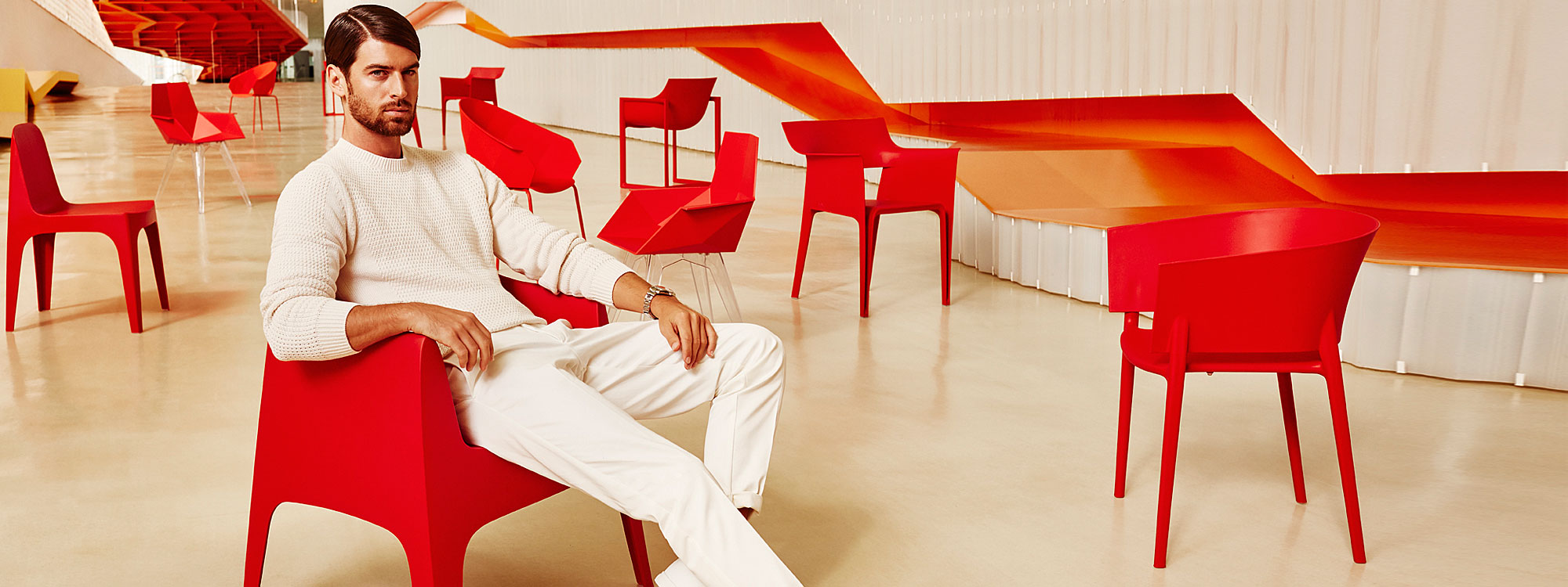 Image of man dressed in white sat on red Solid armchair next to red coloured Africa modern bistro chair by Vondom
