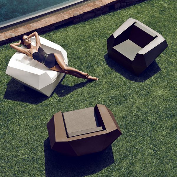 Image of birdseye view of woman stretching out in Vondom Faz white garden lounge chair next to two brown Faz garden chairs