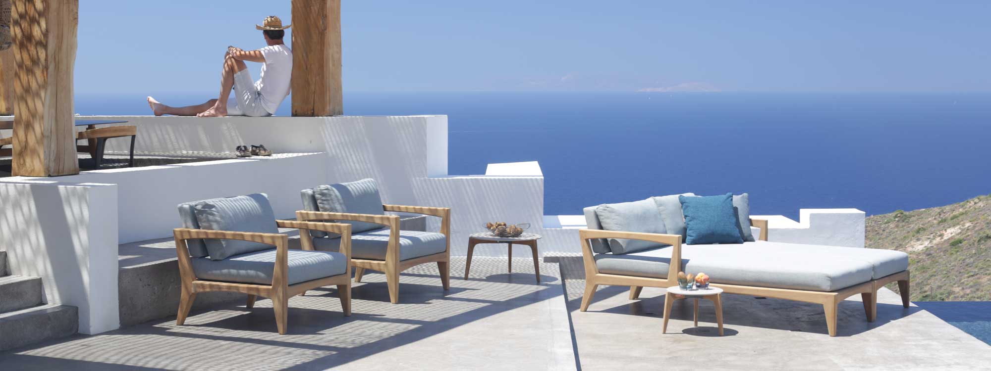 Zenhit teak lounge chairs and daybeds on Greek island terrace overlooking the Mediterranean.