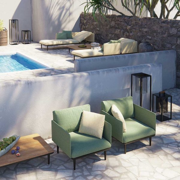 Image of couple of Royal Botania outdoor lounge chairs against wall with swimming pool and daybeds in the background