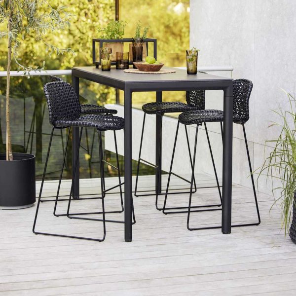 Image of anthracite-colored Vibe bar chairs and Drop bar table by Cane-line on pale wooden decking