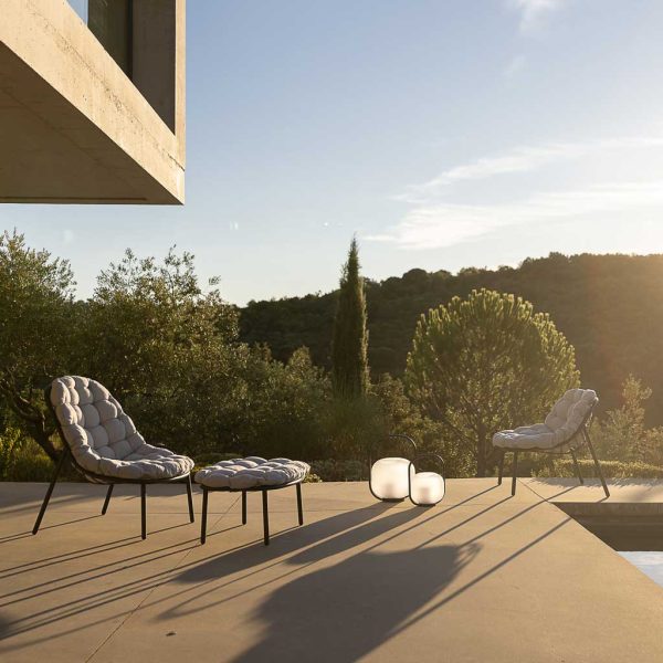 Image of Todus Albus lounge chairs on terrace in late afternoon sun, with Cypress fur tree in background