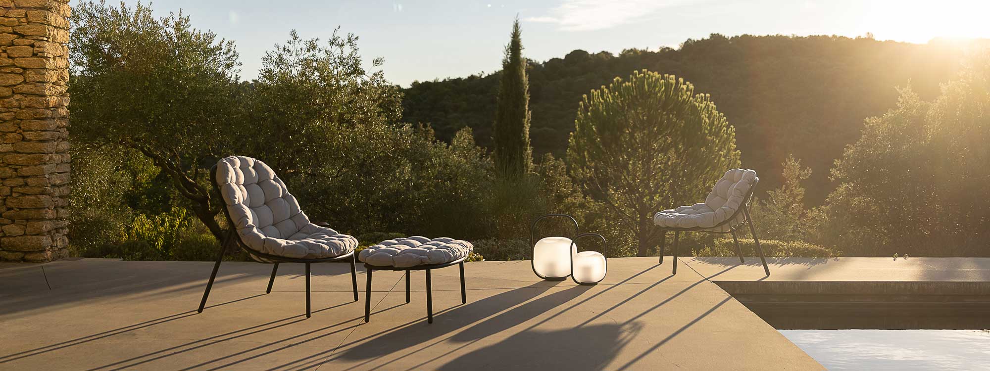 Image of pair of Albus garden lounge chairs and footstool casting long shadows on terrace
