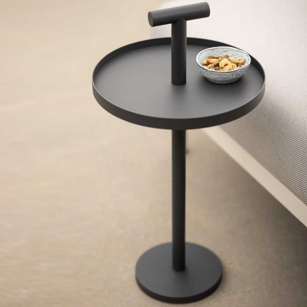 Image of Todus Albus circular outdoor side table with handle, shown in anthracite finish next to white Baza garden sofa