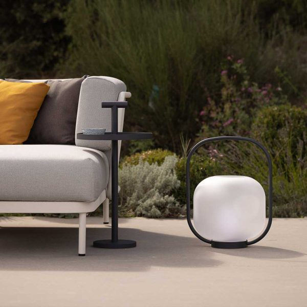 Image of Albus carry side table next to Otus garden lantern and Baza modern outdoor sofa