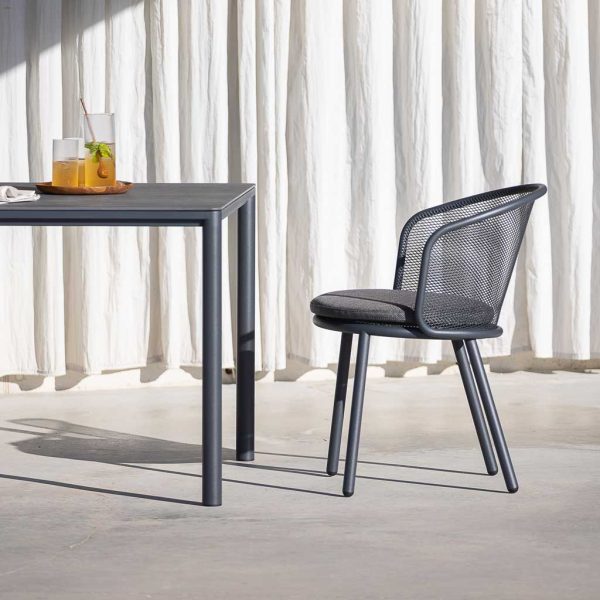 Image of Alca slender garden table and Baza modern outdoor chair on sunny terrace with white drapes in background