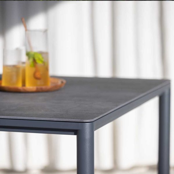 Image showing detail of Alca garden table's round legs and curved corners of the ceramic table top