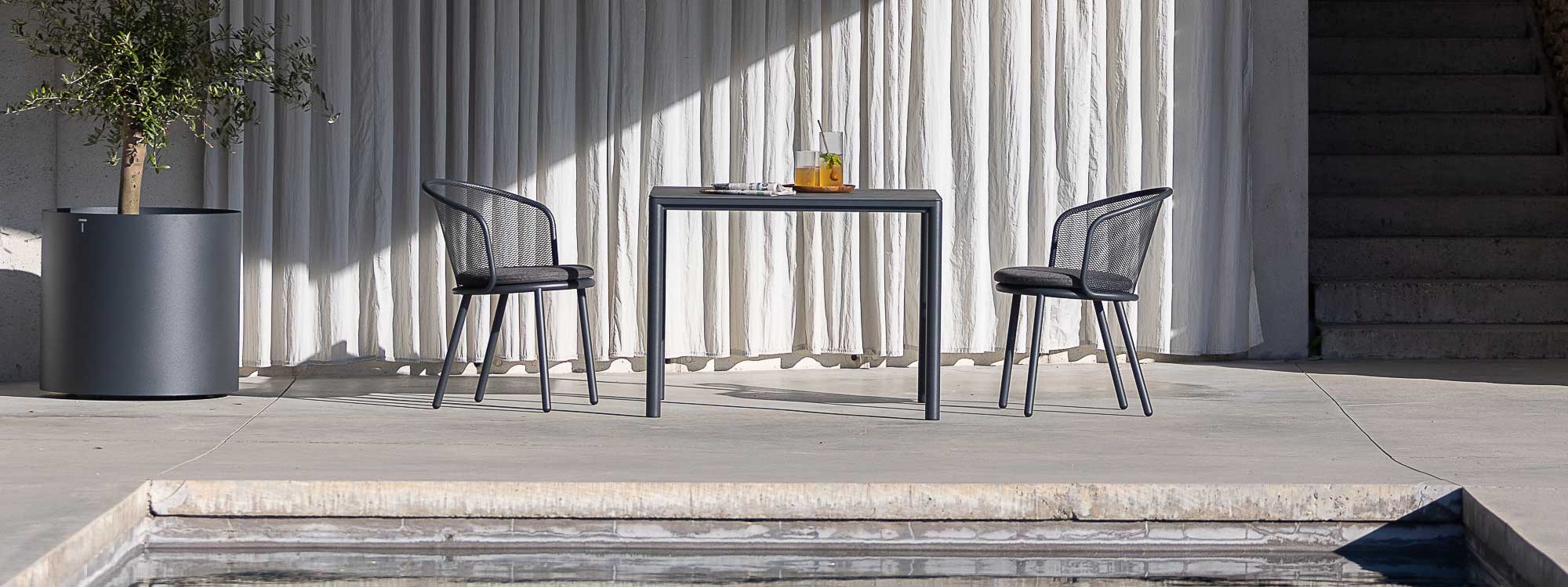Image of Alca square garden table with Branta garden chairs by Todus on sunny terrace