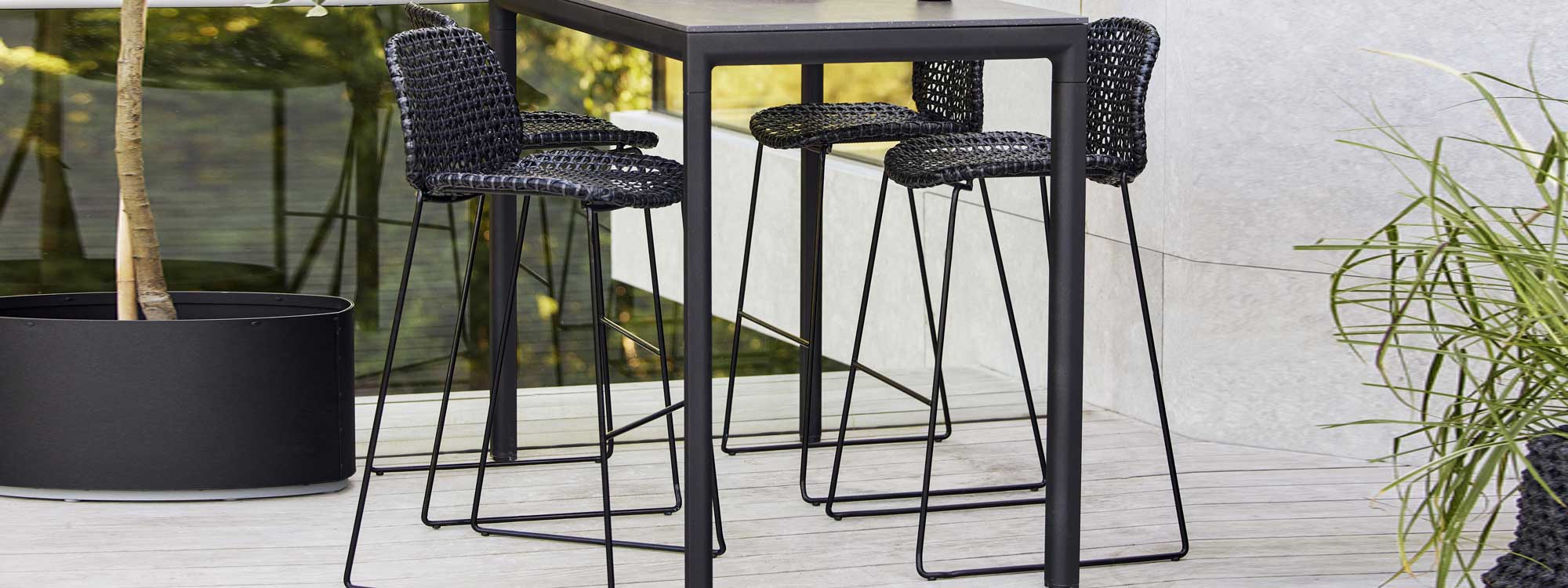 Image of lava-colored Drop bar table and Vibe bar stools on decked terrace by Cane-line outdoor furniture