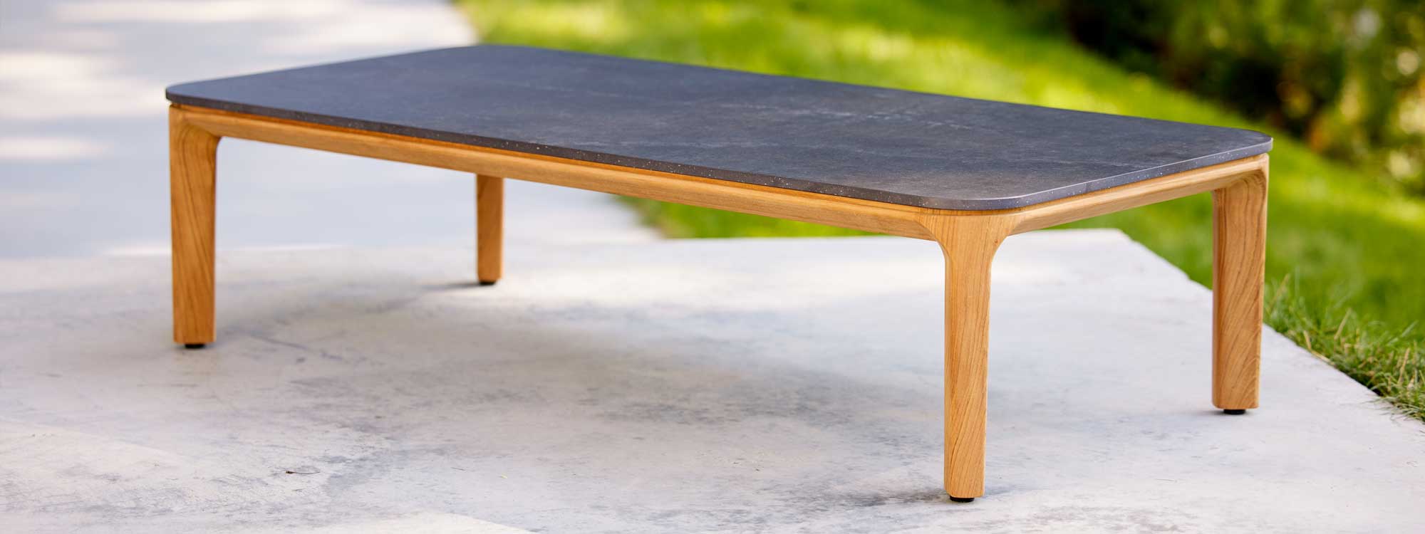 Image of Aspect rectangular low table with teak legs and fossil-black ceramic top by Cane-line garden furniture