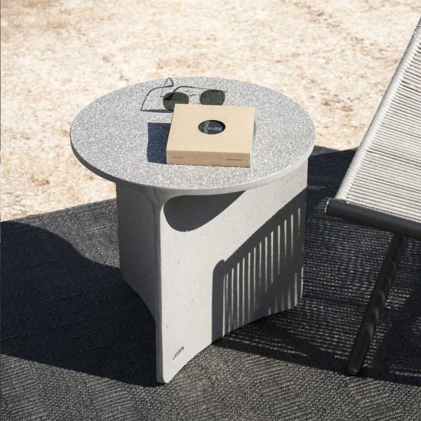 Image of small Aspic concrete outdoor table with sunglasses and book on table top, next to Laze outdoor lounge chair by RODA