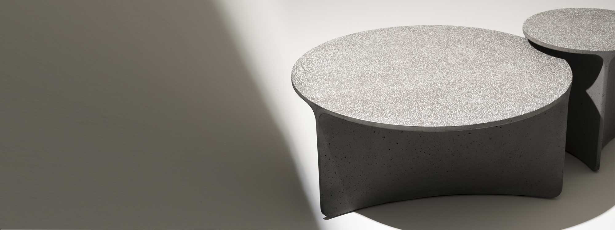 Studio image in light and shade of RODA Aspic concrete low garden tables with shingle suspended in tabletop