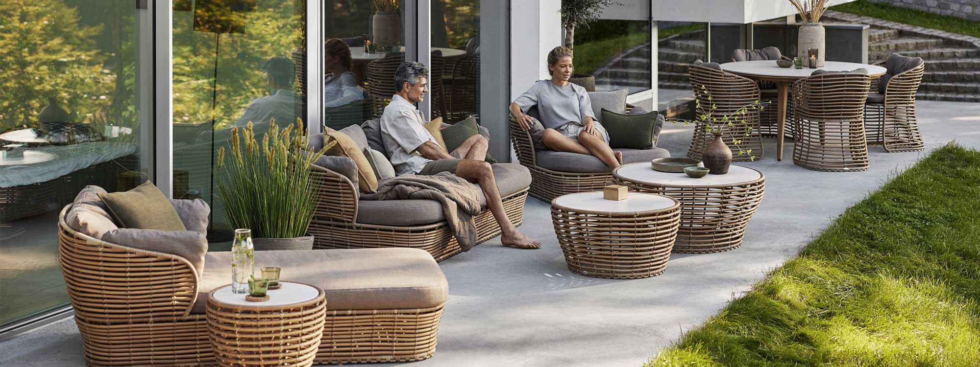 Image of folks sat outside on Basket synthetic can furniture in natural finish by Caneline garden furniture