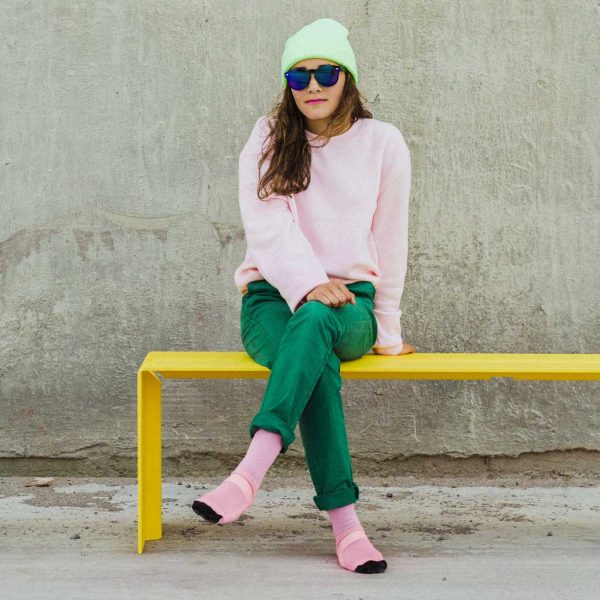 Image of lady hipster sat on Wünder's The Bended yellow bench seat shown against concrete backdrop