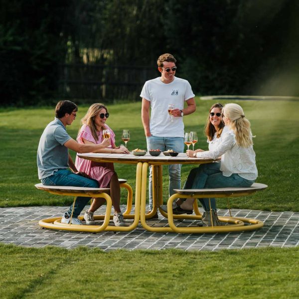 Image of group of friends sat enjoying beers and nibbles around The Circle modern yellow picnic table and benches by Wünder