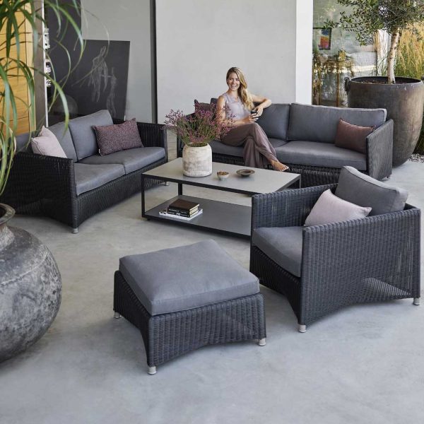 Image of woman sat on Diamond black garden sofa next to Level modern garden coffee table by Cane-line