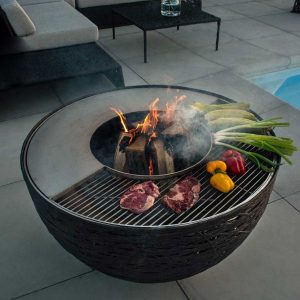 Image of steaks and vegetables cooking on stainless steel grill of Lava Nest bbq and firepit by Unknown Nordic