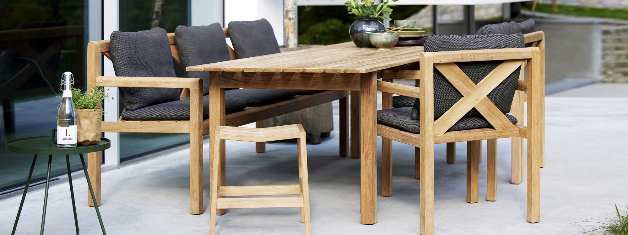 Image of Flip teak stool and Grace teak dining set with grey cushions by Cane-line garden furniture