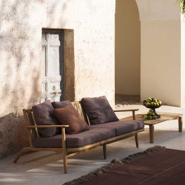 Image of RODA Levante 2 seater teak sofa with brown cushions, next to Levante garden low table and Triptyque outdoor carpet