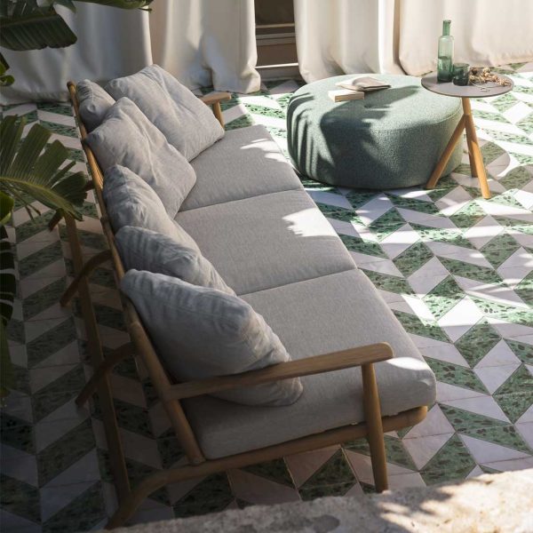 Image of RODA Levante teak garden sofa, Double round pouf and Root side table shown on green and white tiled floor