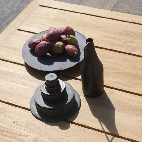 Image of detail of RODA Levante teak low table's planked top, with bowl of figs, bottle and pile of stacked measuring weights