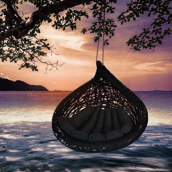 Image of black Bios Lucid swing seat with grey cushion by Unknown Nordic, beneath tree on beach at dusk