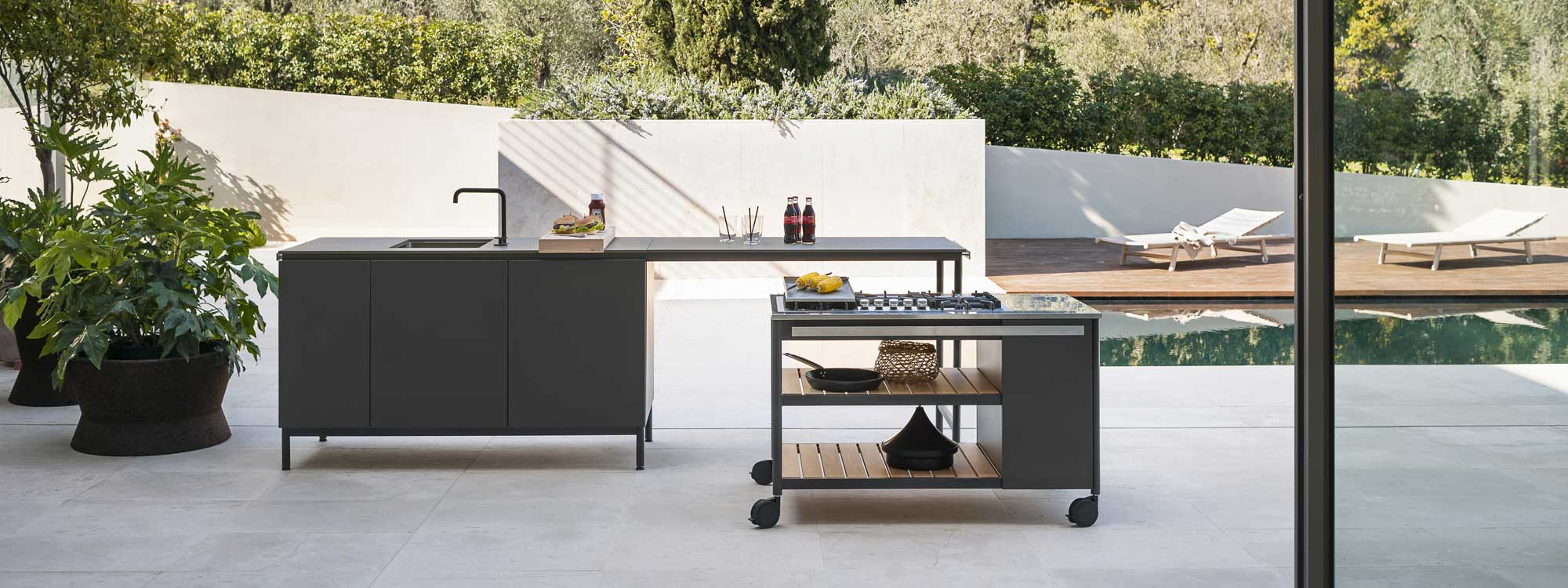 Image of RODA's Norma modern outdoor kitchen and gas bbq with Bush On cork planter to the side and Orson teak sun loungers in background next to swimming pool