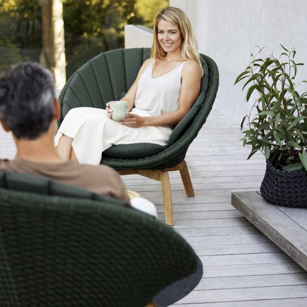 Image of man and woman sat in dark grey Peacock garden lounge furniture by Cane-line