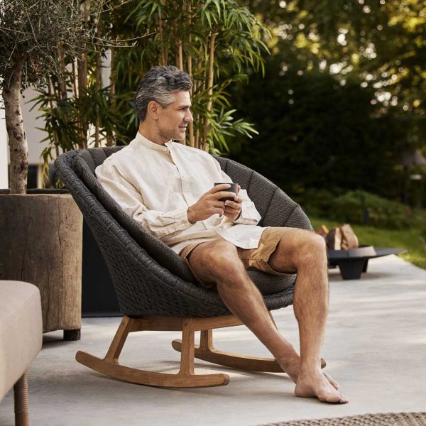 Image of man relaxing on outdoor terrace whilst sat in Peacock rocking chair by Cane-line