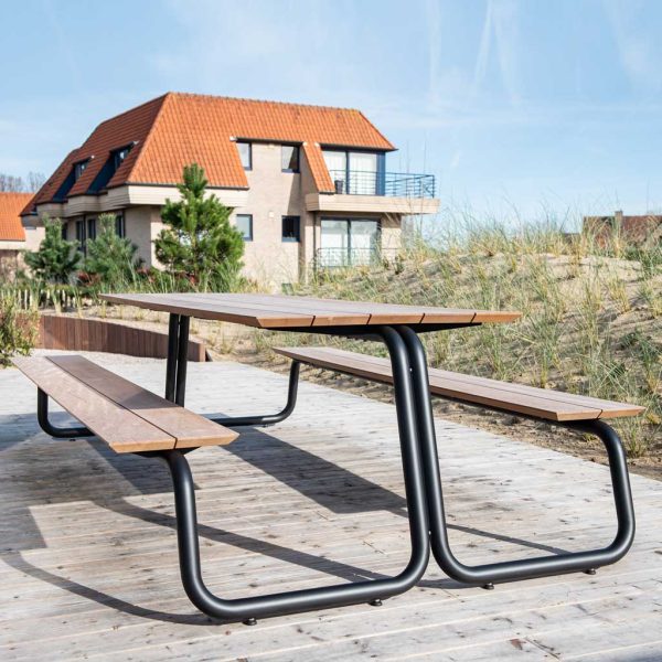 Image of Wünder The Table modern picnic table with benches on wooden decking with house and sand dune in the background