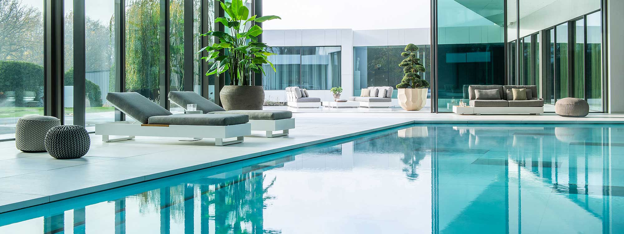 Image of Bari minimalist sun loungers and garden sofa in white around luxurious indoor swimming pool