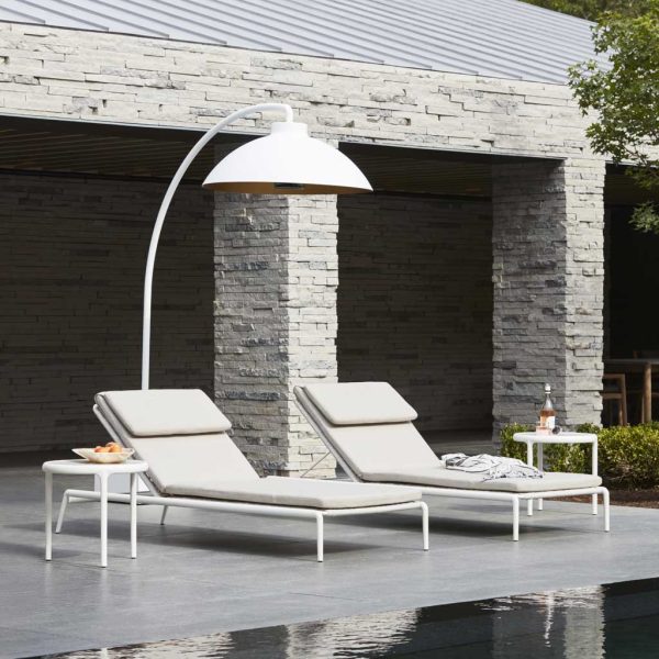 Image of white Heatsail Dome heater on poolside above pair of sun loungers