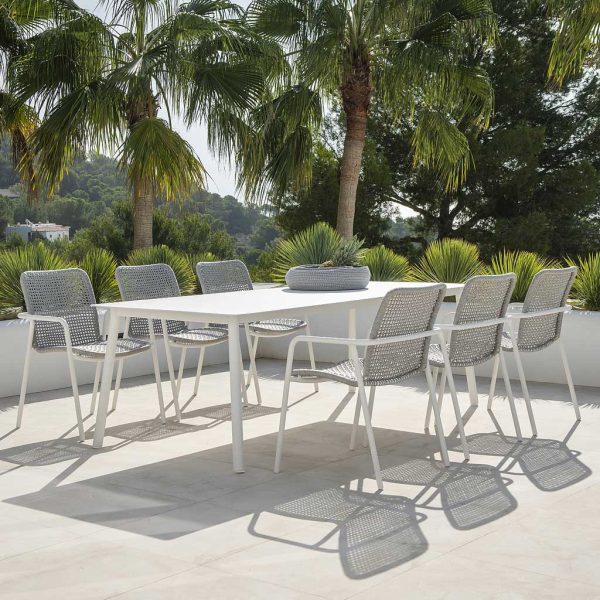 Image of Durham modern aluminium garden dining set in white finish, shown on sunny terrace with exotic plants and trees in the background